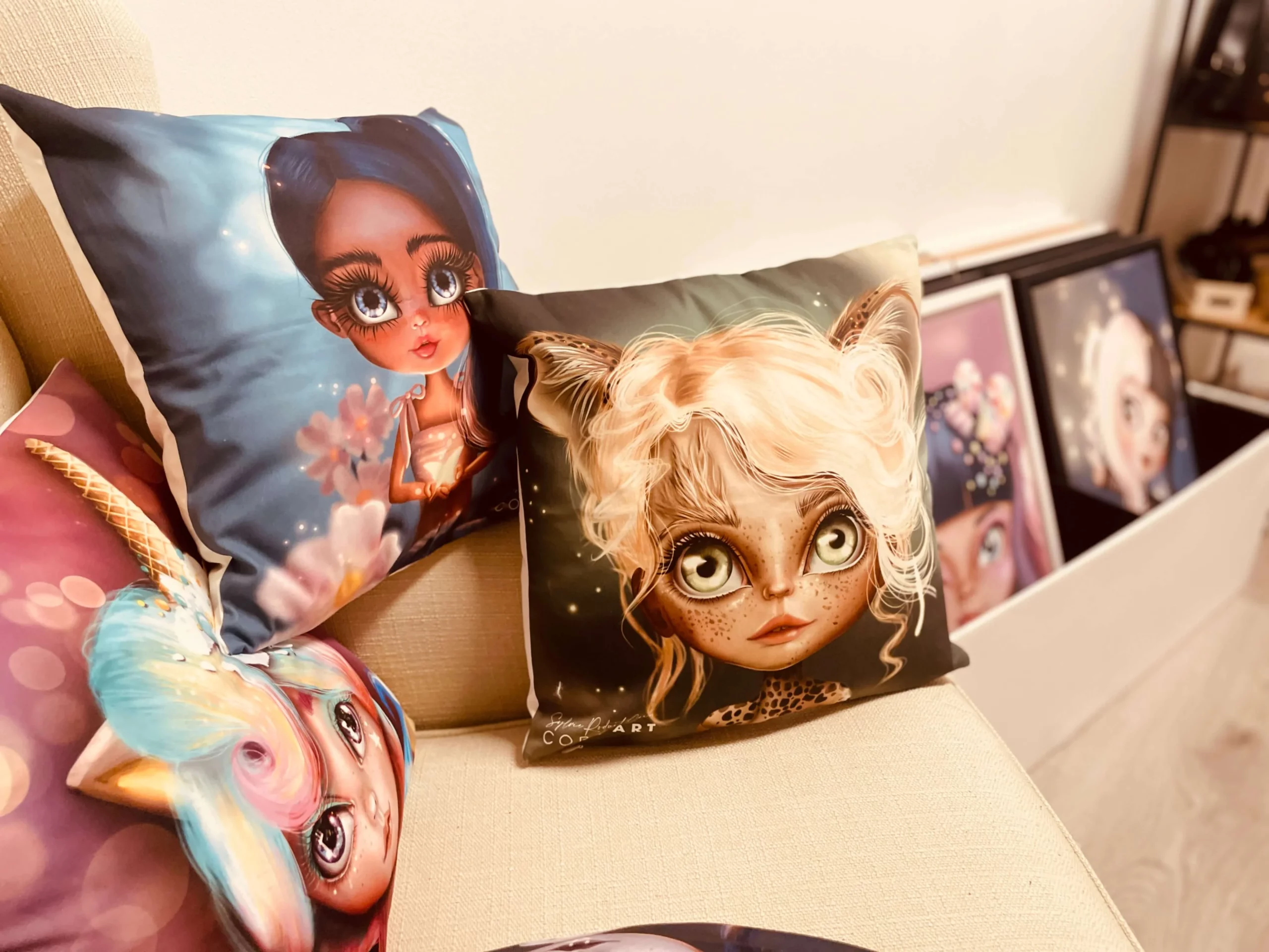 Coussins décoratifs illustrés par Sylvie Roduit, présentant des personnages expressifs de l’univers Coroart.