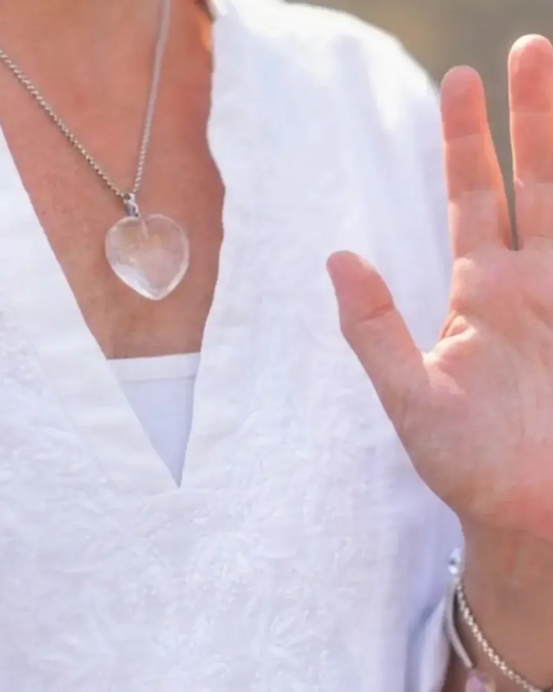 Femme pratiquant un soin énergétique avec les mains levées.