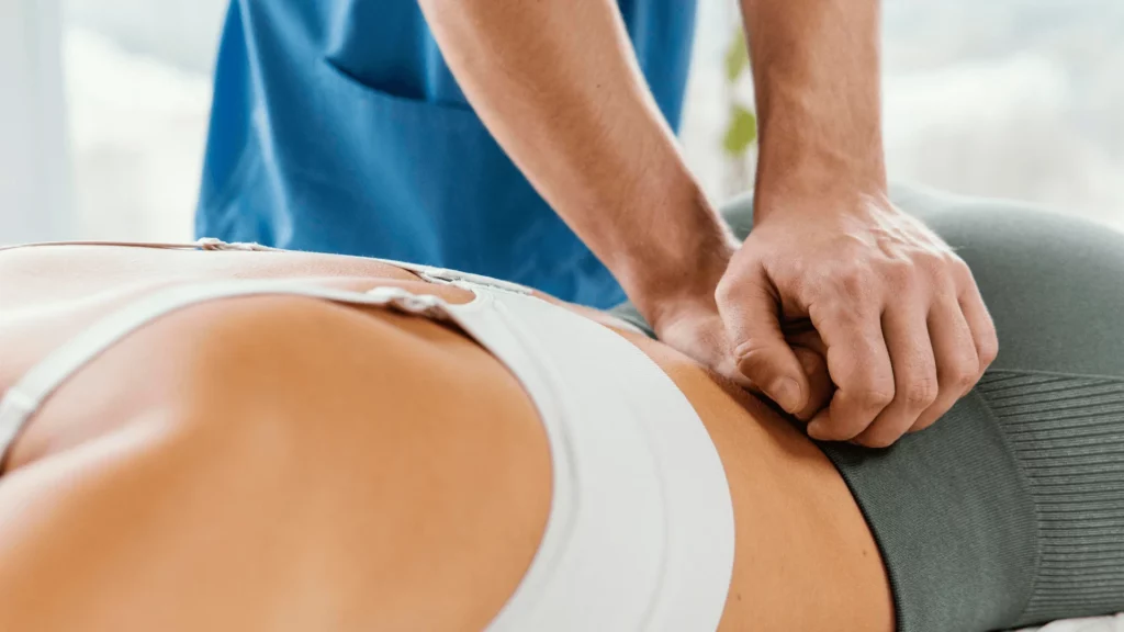 Visualisation précise de la technique de Muscle Energy pour le bassin, montrant le placement des mains pour l'ajustement du sacrum sur une patiente par Sophie Antille